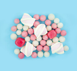 Dragees and marshmallows on a blue background. Colored sweet candies top view