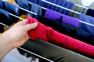 female hands hang wet clothes close-up, laundry hanging and drying on wire room dryer, home chores concept, cleaning clothes, proper washing of cotton colored fabrics, selective focus