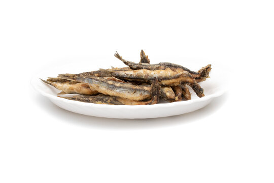 A white plate with fried anchovies, isolated on white background. Spanish food concept.