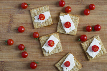 Top View of Red Tomatoes with Cheese and Crackers on Wood