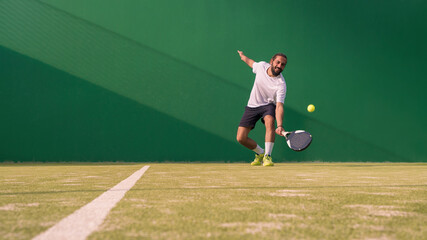 Professional monitor of padel jump to the ball with a black racket. Sport game