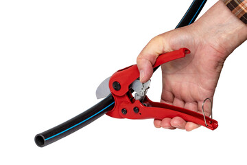 Plumber tools isolated. A man accurately cuts a piece of PE pressure pipe or water pipe with a red pvc pipe cutter. Clipping path. Drinking and service water systems.