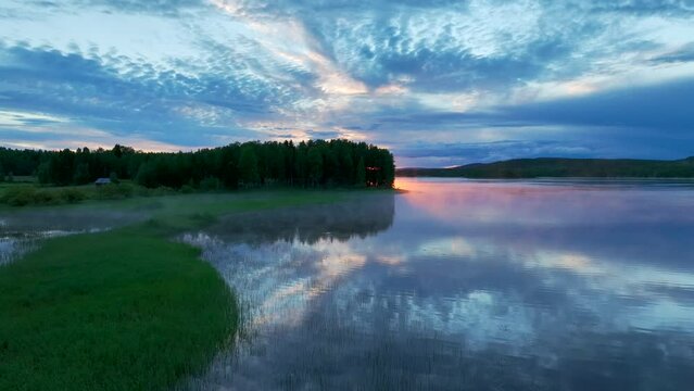 Aerial view of sunset over calm lake during midnight sun in Overtornea, Sweden.