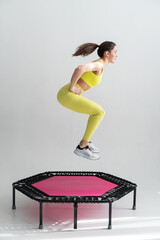 young fitness woman In sportswear jumping on sport trampoline - obrazy, fototapety, plakaty