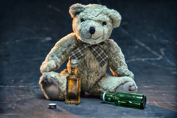 The Teddy bear symbolizing a child. Drunk teddy bear sitting on the floor and drinking whiskey...