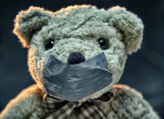 Teddy bear symbolizing a child. Close up of the muzzle of teddy bear with taped mouth