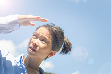 Asian woman shields herself from the sun on a scorching summer day.