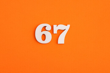 White wooden number 67 on eva rubber orange background