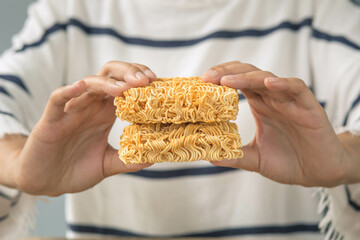 A woman's hand holds dry instant noodles ready to eat.