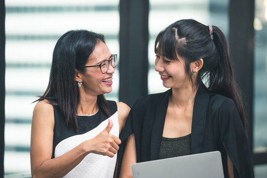 Two young business asian woman working together in office space. Asia business female people group meeting room conference desk real office team.