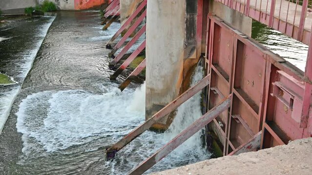 water breaks through a village dam in a crack, on a small river, selective focus.