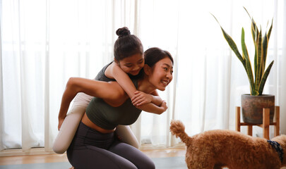 Happy and Healthy famly Mother and little daughter practice yoga and fitness at home ,Healthy Little daughter enjoys riding the back of her mother during yoga exercise at home