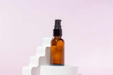 Amber glass pomp bottle with black lid on a podium on light pink background. Skincare products ,...