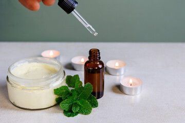 Fototapeta na wymiar jar of body butter with mint and dropper with candles