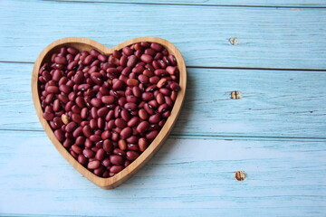 Kidney beans, red beans in heart shaped wooden bowl on wooden table, top view and with copy space.