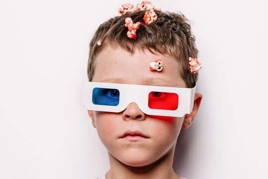 Boy in 3D glasses with popcorn over head in studio