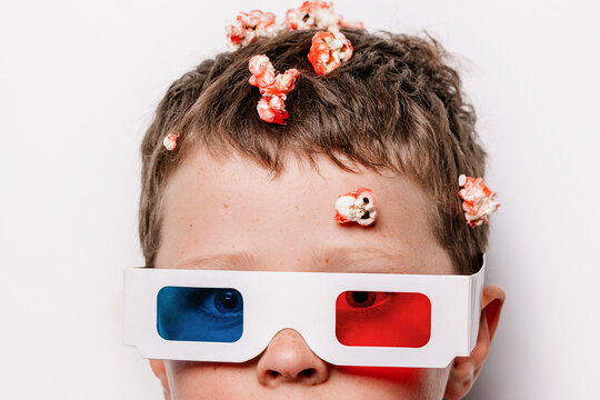 Boy in 3D glasses with popcorn over head in studio