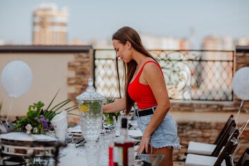 Woman in red body and shorts is surfing birthday table with glasses and meal.