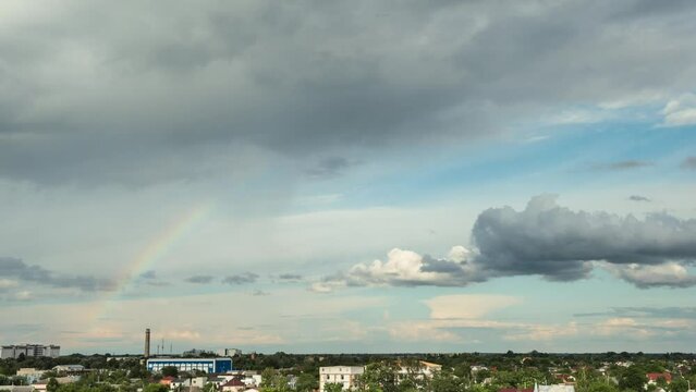 Big rainbow appears in the sky after the rain. Clouds moving fast in a timelapse. Summer skies after heavy rain