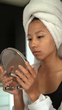 oung lady with towel on head look in mirror 