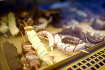 Obraz premium Choice of sweets on traditional street Christmas market in Krakow, Poland. Famous fruits, candy, cookies, gingerbread in chocolate glaze on skewers in bakery Xmas Eve.