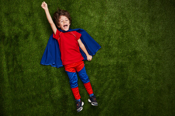 Happy little superhero on lawn