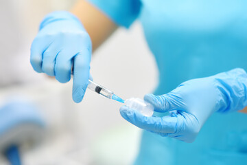 The female surgeon is dialing medicine into a syringe. Doctor is preparing to give an injection to the patient in operation room.