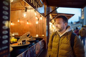 Obraz na płótnie Canvas Mature man buying street food on european Christmas market. Hot soup is a traditional local cuisine in winter season