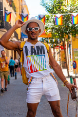 Fototapeta na wymiar Portrait of a gay black ethnic man at the pride party taking photos with a hat, LGBT flag