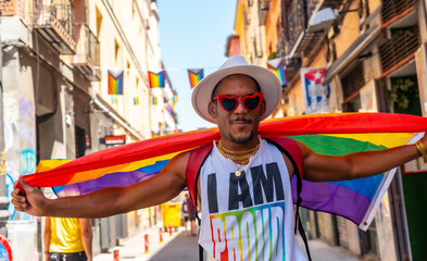 A gay black man walking at the pride party with an LGBT flag