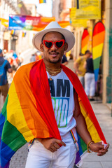 Portrait of a gay black man walking at the pride party with an LGBT flag