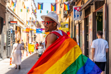 A gay black man walking at the pride party with an LGBT flag, walking backwards