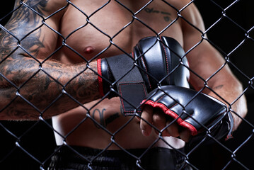 Professional kickboxing fighter puts on gloves in a cage ring. The concept of sports, Muay Thai, martial arts.