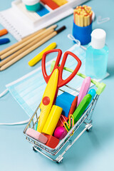 School supplies, poppit anti-stress, face mask, bottle of sanitizer, for back to school on a blue background. Covid-19 precautions, staying healthy.