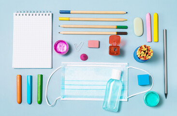 School supplies, poppit anti-stress, face mask, bottle of sanitizer, for back to school on a blue background. Covid-19 precautions, staying healthy. Top view flat lay.
