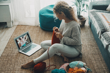Woman at home doing knit work for hobby and leisure activity alone watching tutorial on line on...