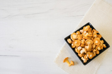 Young, yellow Cantharellus mushrooms lie in a black square plate on the table. The idea of cooking forest mushrooms. High quality photo