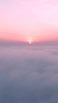 Aerial vertical shot of clouds with pink sunset on top