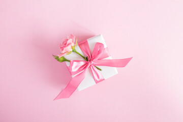Gift box with pink rose on the pink  background.Top view. Copy space.