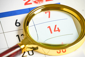 Calendar with number fourteen under magnifying glass.
