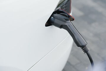 Close up of the Hybrid car electric charger station with power supply plugged into an electric car being charged.