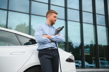 a businessman charges an electric car.