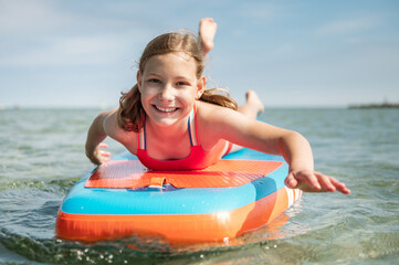 Happy teen girl lying on SUP board and enjoy water
