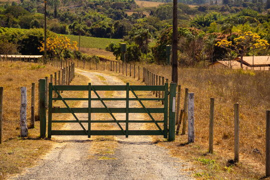 Uma porteira de madeira pintada de verde na entrada de uma fazenda. Paisagem de beira de rodovia em Goi&aacute;s.