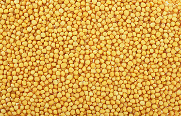 Organic yellow mustard seeds as background, top view.