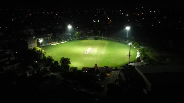 Drone orbiting around a cricket stadium during a match at night. 