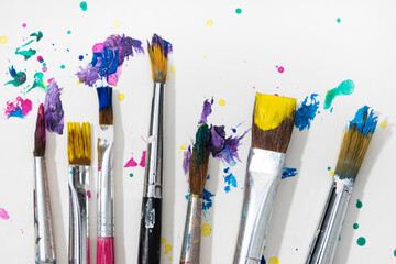 Group of Art Paint brushes and colorful splatter on white canvas paper