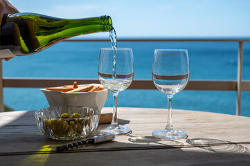 Pouring of txakoli or chacolí slightly sparkling very dry white wine produced in the Spanish Basque Country, served outdoor with view on Bay of Biscay, Atlantic Ocean.