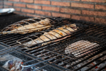 Fresh fish grilling on old charcoal parrillas build outside of buildings in small fisherman's village Getaria, Basque Country, Spain