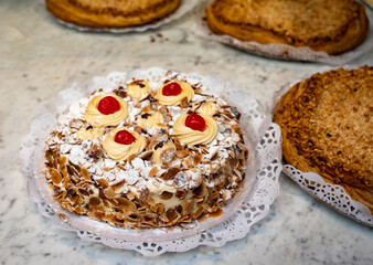 Cake with cream and roasted almond nuts on display in artisanal bakery in San Sebastian city, Basque Country, Spain